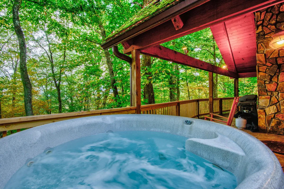 This image features a wooden deck nestled in the forest, with a relaxing hot tub as the focal point. The surrounding trees and tranquil setting convey a deep connection to nature, with the hot tub perfectly positioned to enjoy scenic views or sunsets after a day of adventure.